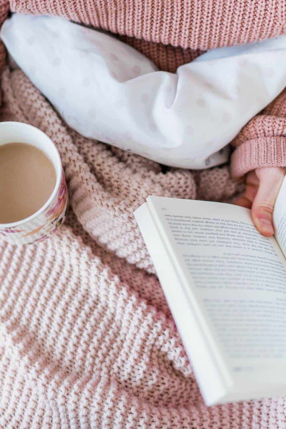 A woman reading in bed with a cup of coffee